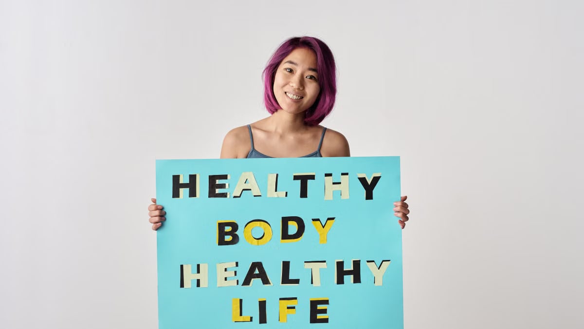 A young woman with purple hair holding a poster promoting a healthy lifestyle.